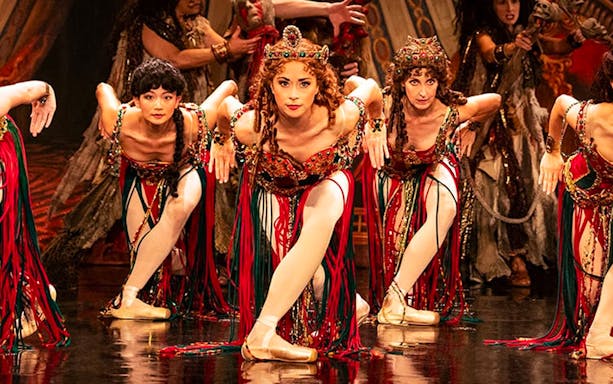 Performers in vibrant costumes during a Phantom of the Opera dance scene.