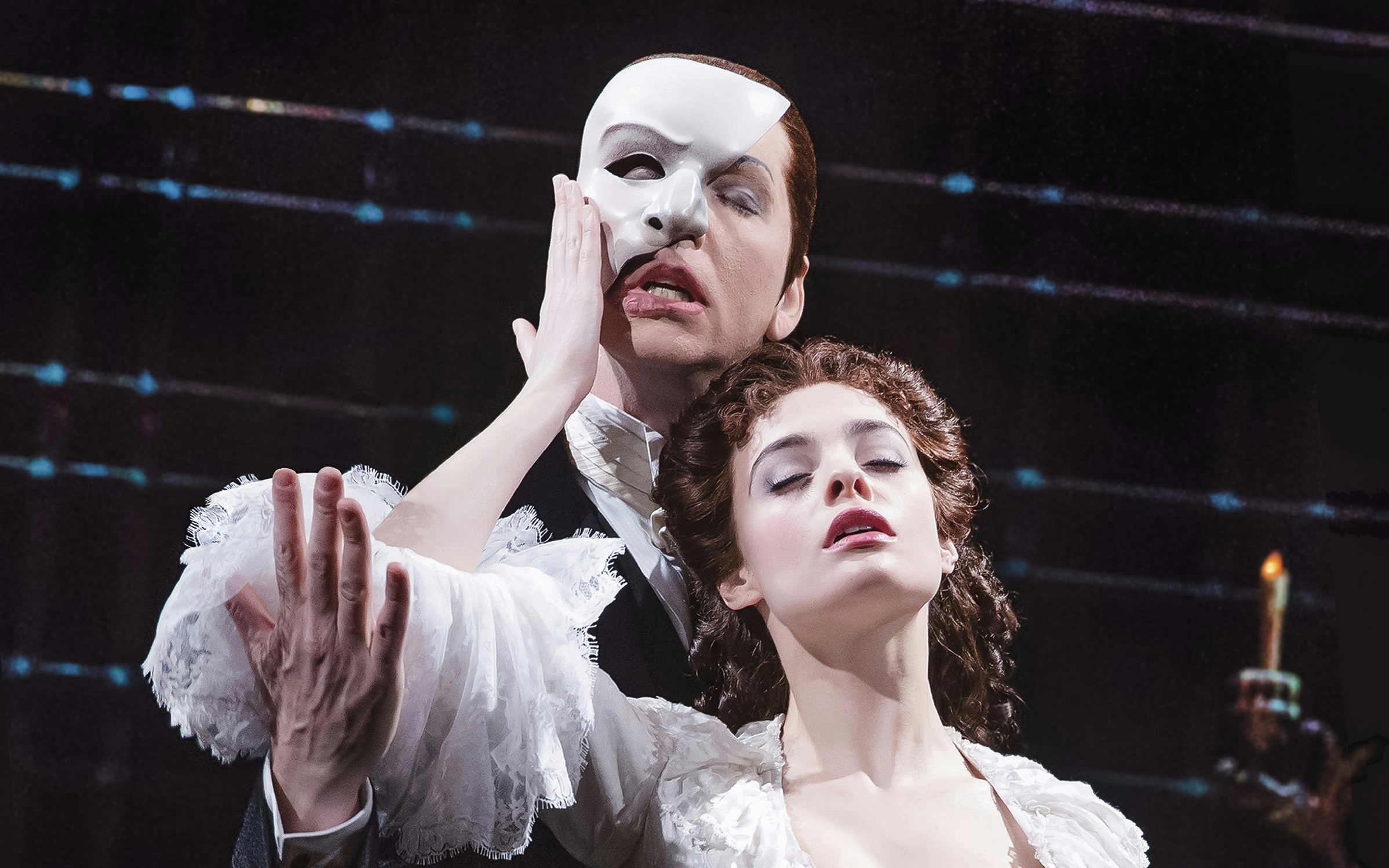 Phantom of the Opera scene with masked figure and woman on stage.