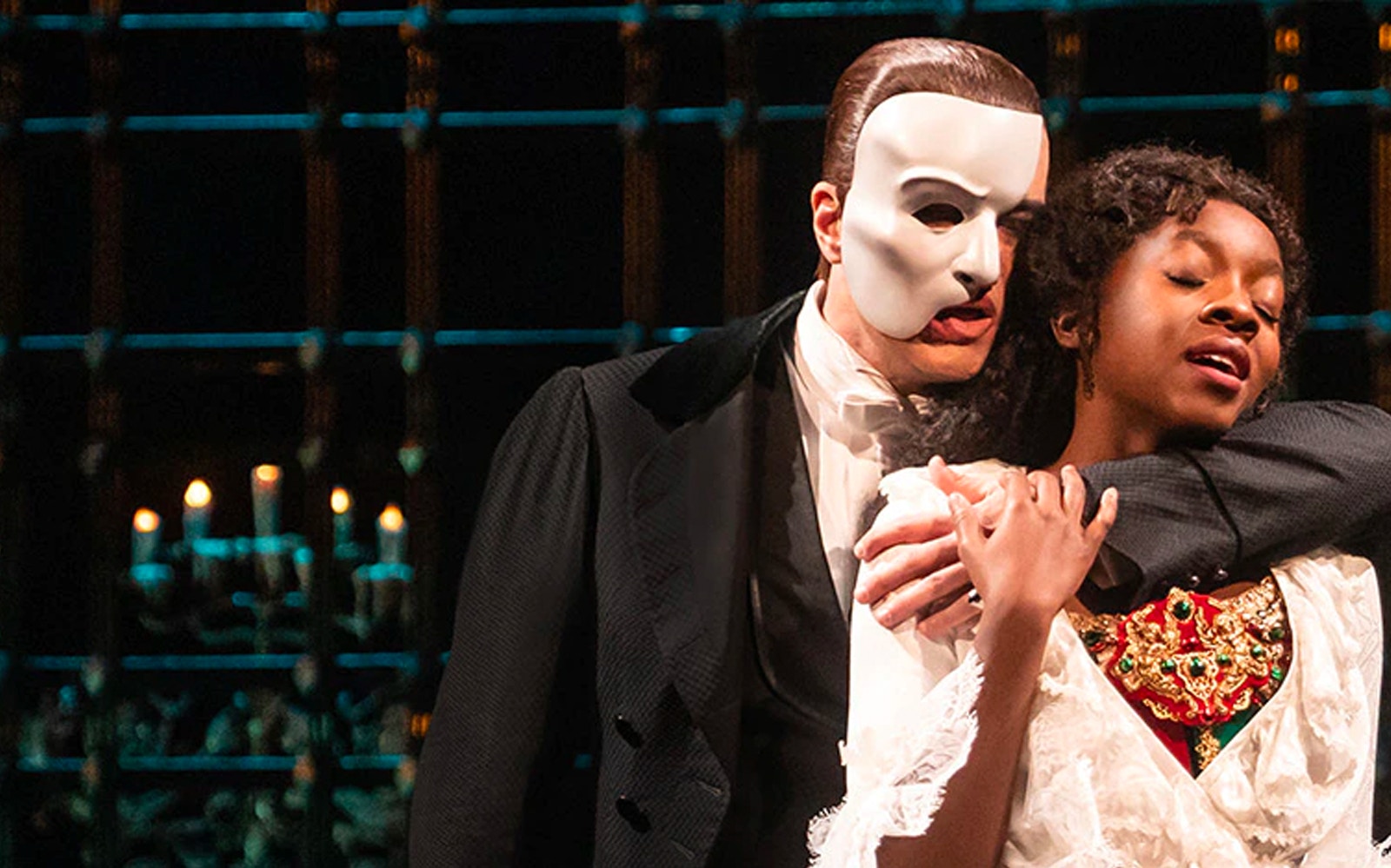 Phantom of the Opera scene with masked character embracing a woman on stage.