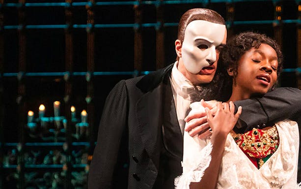 Phantom of the Opera scene with masked character embracing a woman on stage.