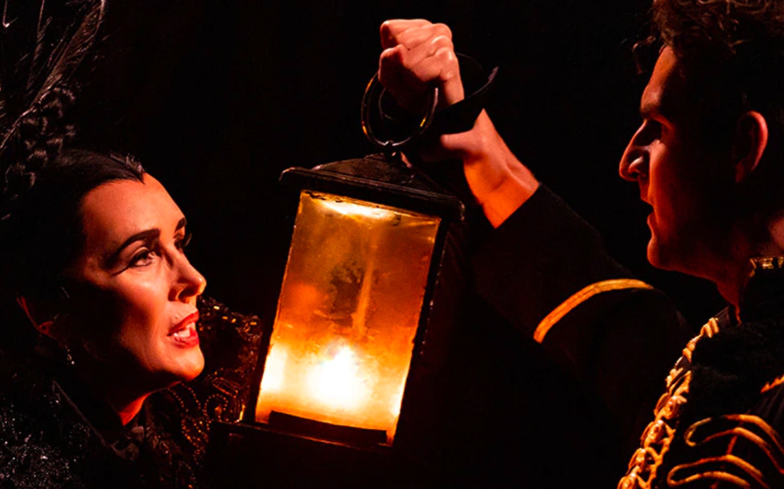 Actors holding a lantern in a scene from Phantom of the Opera.