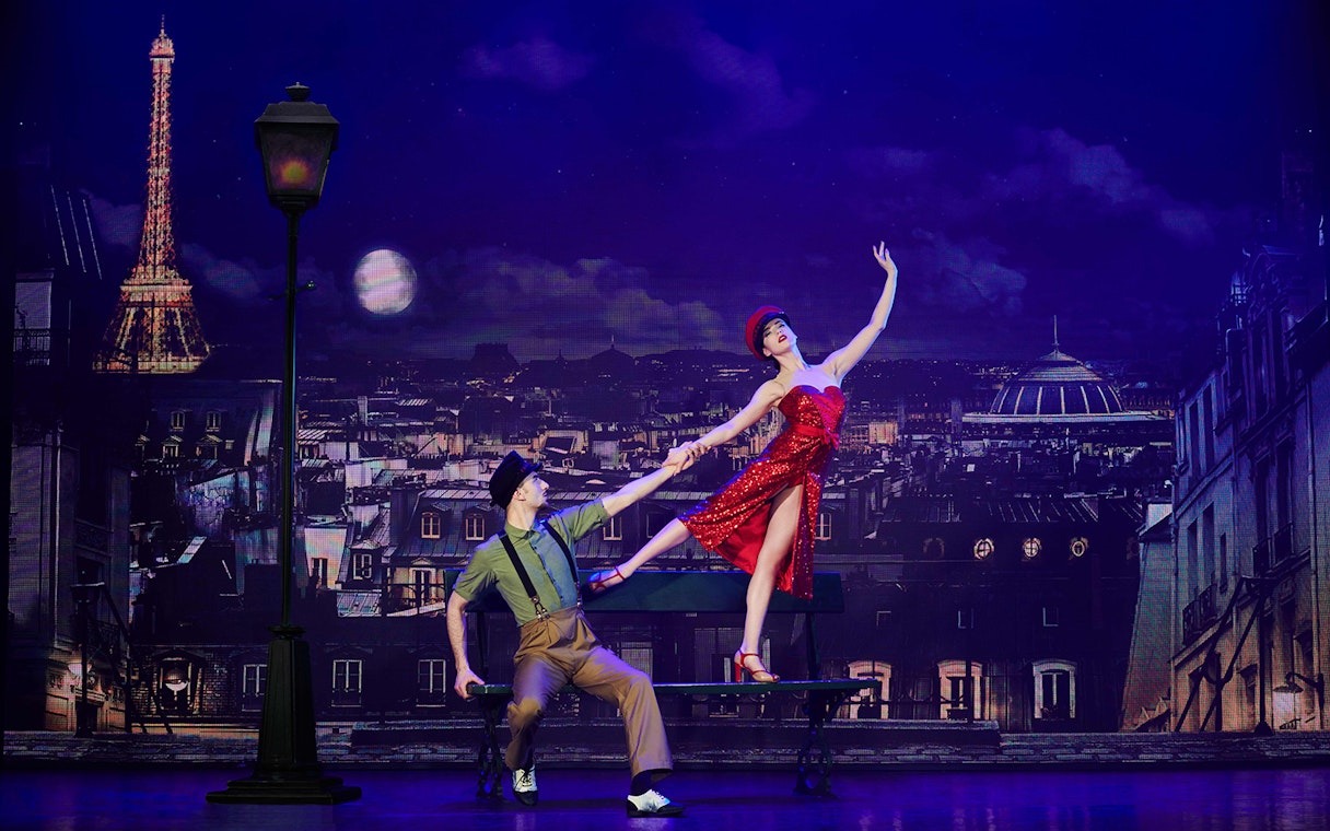 Dancers performing at Paradis Latin show in Paris with Eiffel Tower backdrop.
