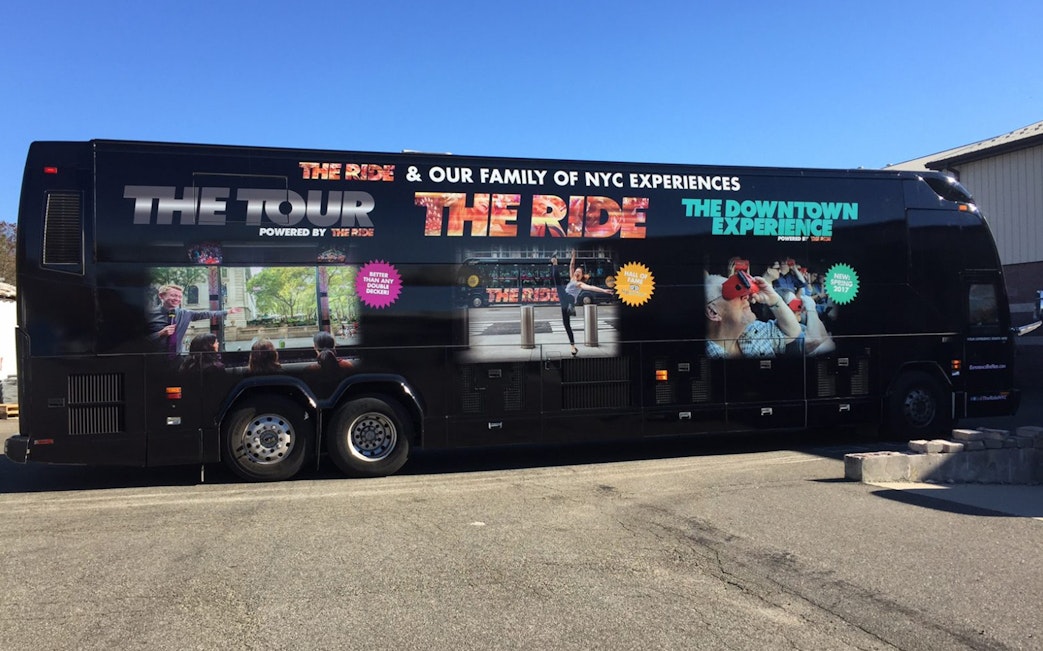 Tour bus for "The Ride" experience in NYC, featuring city attractions and interactive performances.