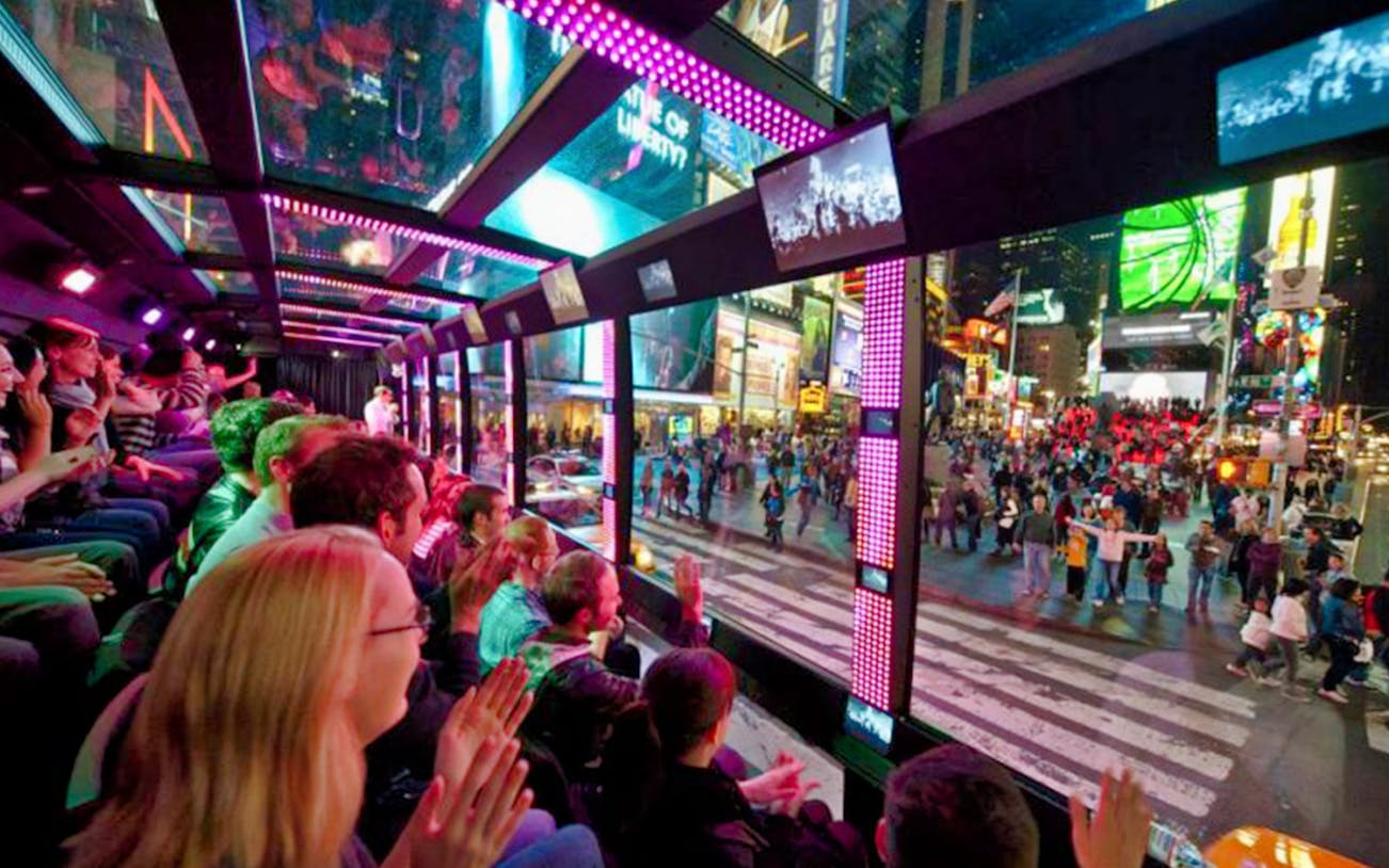 Double-decker bus with tourists on "The Tour - The Ride" in New York City, passing Times Square.
