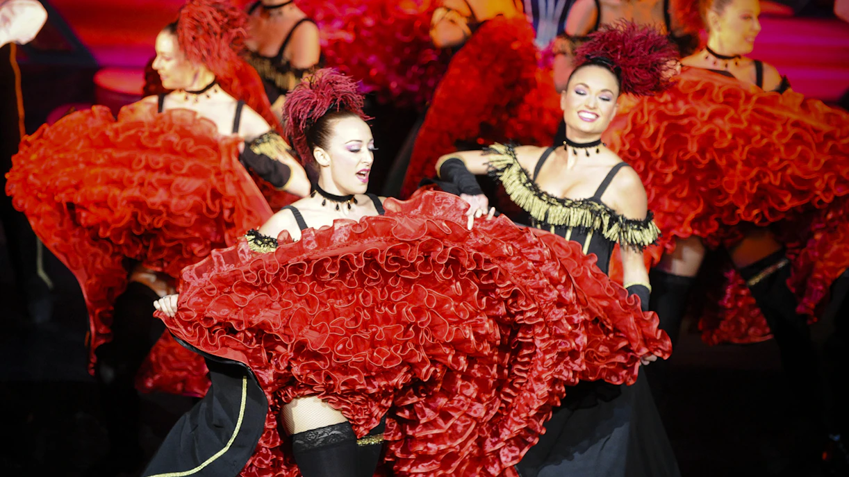 Dancers performing at Paradis Latin show in Paris with vibrant red costumes.
