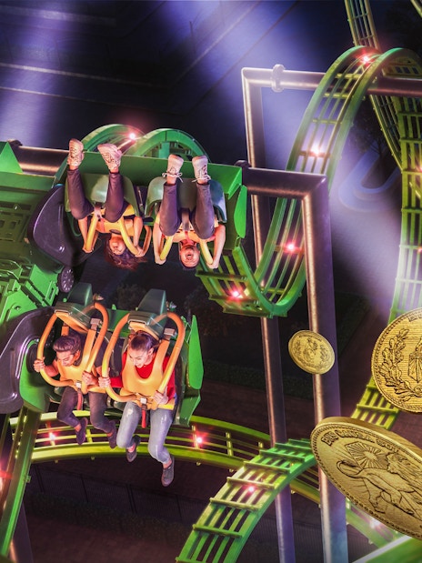 Roller coaster ride at MOTIONGATE™ Dubai with riders upside down on a green track.