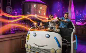 Family enjoying Ghostbusters ride at MOTIONGATE™ Dubai with neon effects.