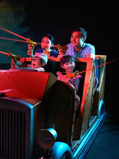 Family enjoying interactive ride at LEGOLAND® Dubai with LEGO characters and laser guns.