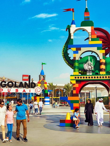 Family walking in front of Legoland Dubai entrance with colorful Lego dragon arch.