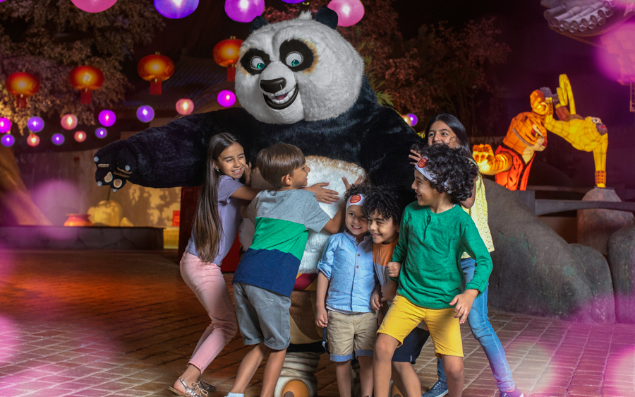 Children interacting with a panda character at Dubai Parks and Resorts.