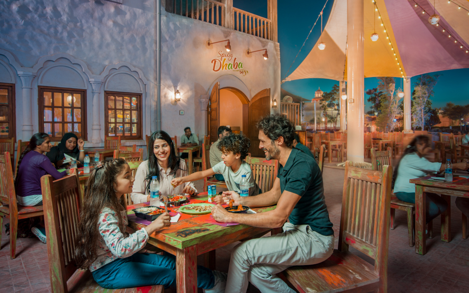 Family dining at Spicy Dhaba in Dubai Parks and Resorts, enjoying a meal under colorful canopies.