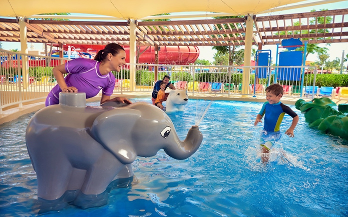 Child playing near elephant water feature at LEGOLAND Water Park Dubai.