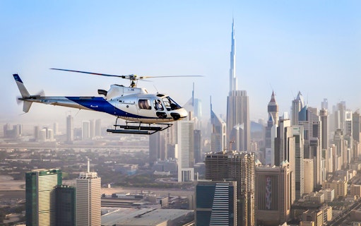 Helicopter flying over Dubai skyline with Burj Khalifa in view.