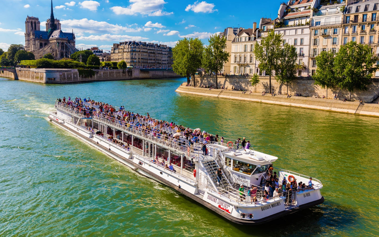 Seine River cruise with tourists viewing the Eiffel Tower in Paris.