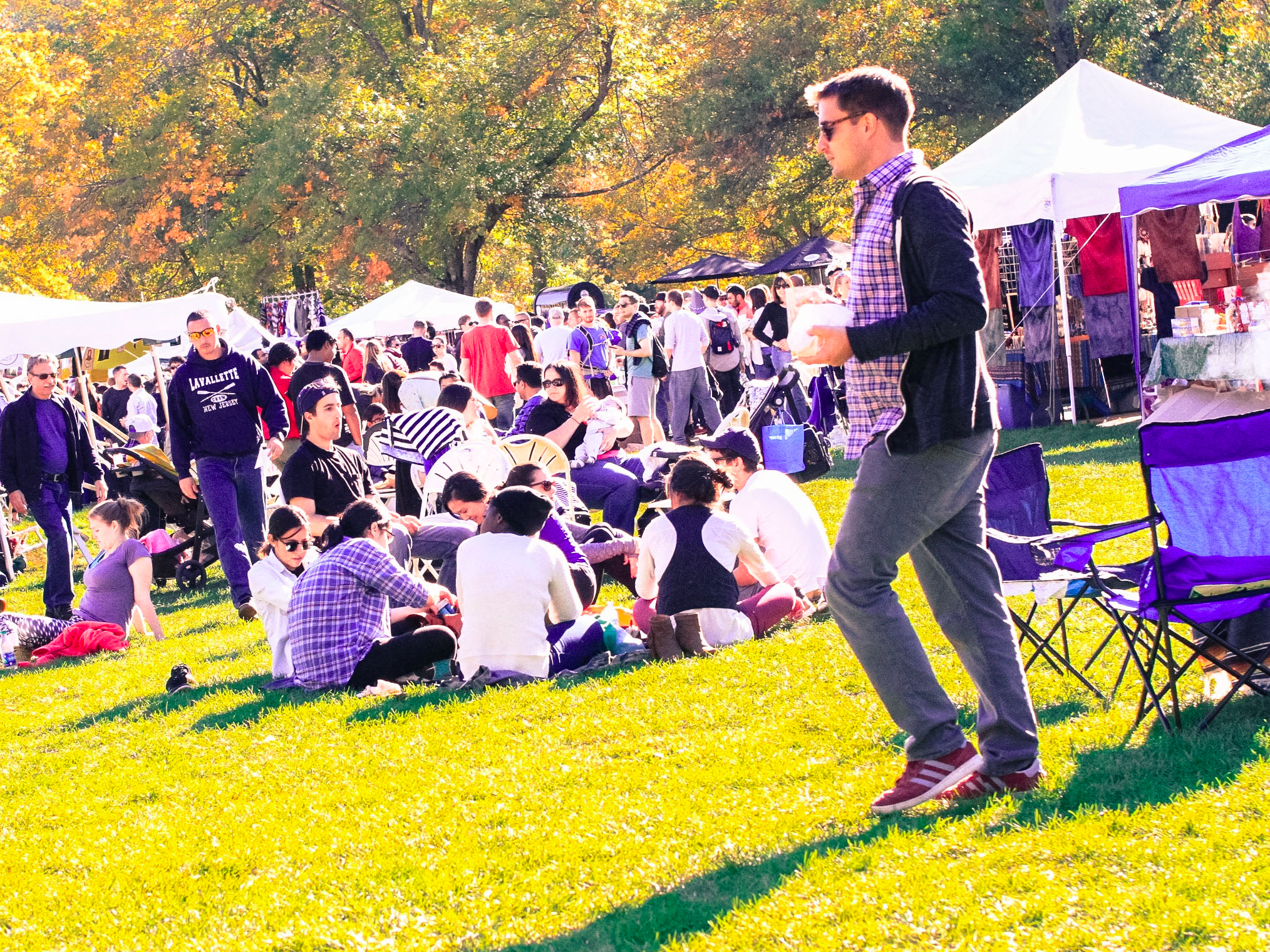 People enjoying Bear Mountain Oktoberfest 2016 with tents and autumn trees in the background.
