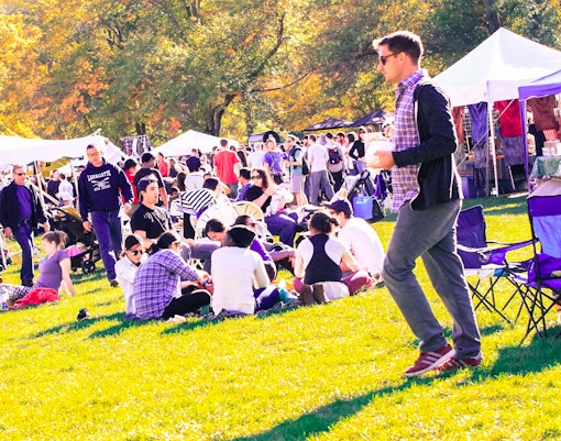 People enjoying Bear Mountain Oktoberfest 2016 with tents and autumn trees in the background.