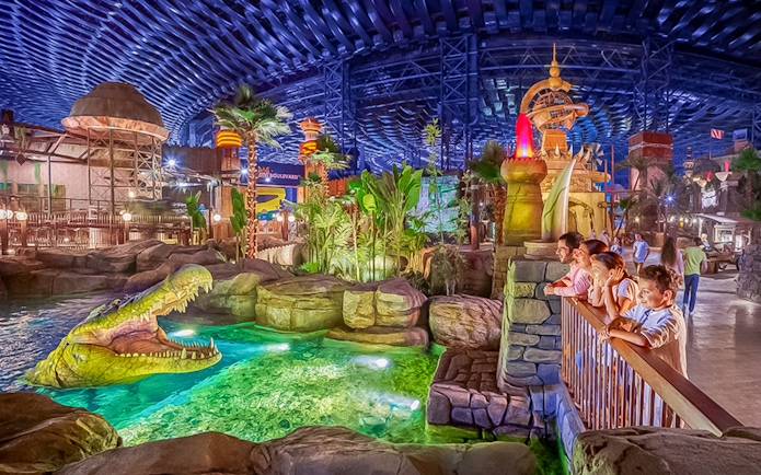 Visitors observing animatronic crocodile at IMG Worlds of Adventure, Dubai indoor theme park.