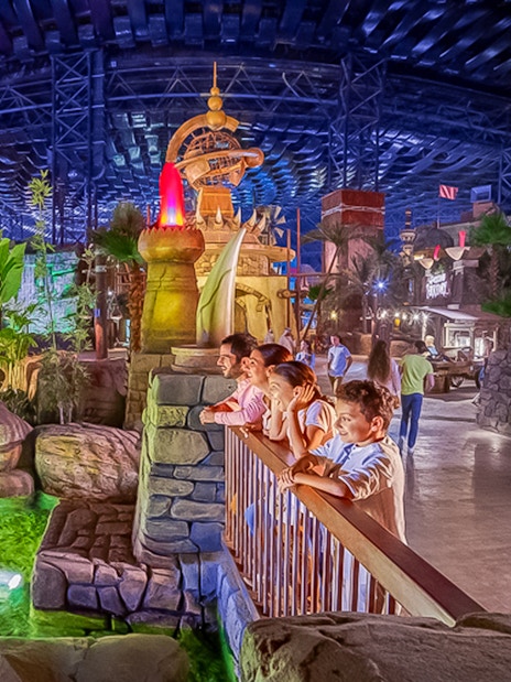 Visitors observing animatronic crocodile at IMG Worlds of Adventure, Dubai indoor theme park.