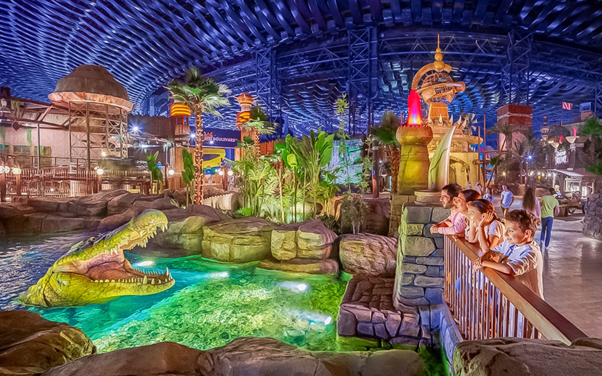 Visitors observing animatronic crocodile at IMG Worlds of Adventure, Dubai indoor theme park.
