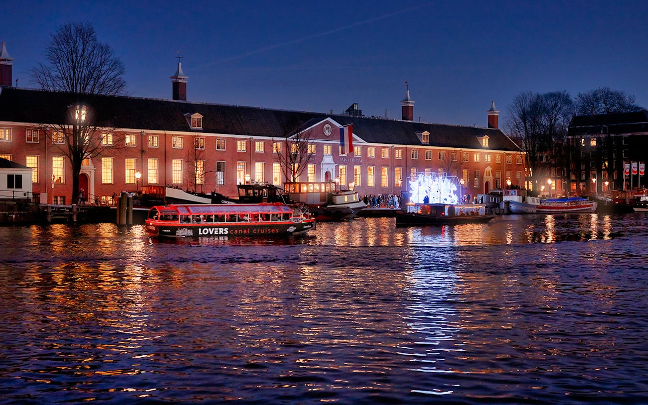 Canal cruise in Amsterdam at night with illuminated buildings and boats.