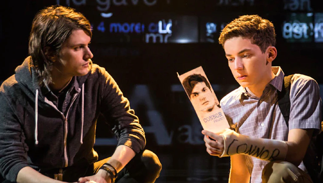 Two actors on stage in a scene from the musical "Dear Evan Hansen," one holding a letter.