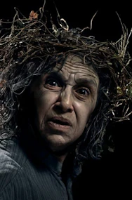 King Lear character with wild hair and intense expression at Shakespeare's Globe.