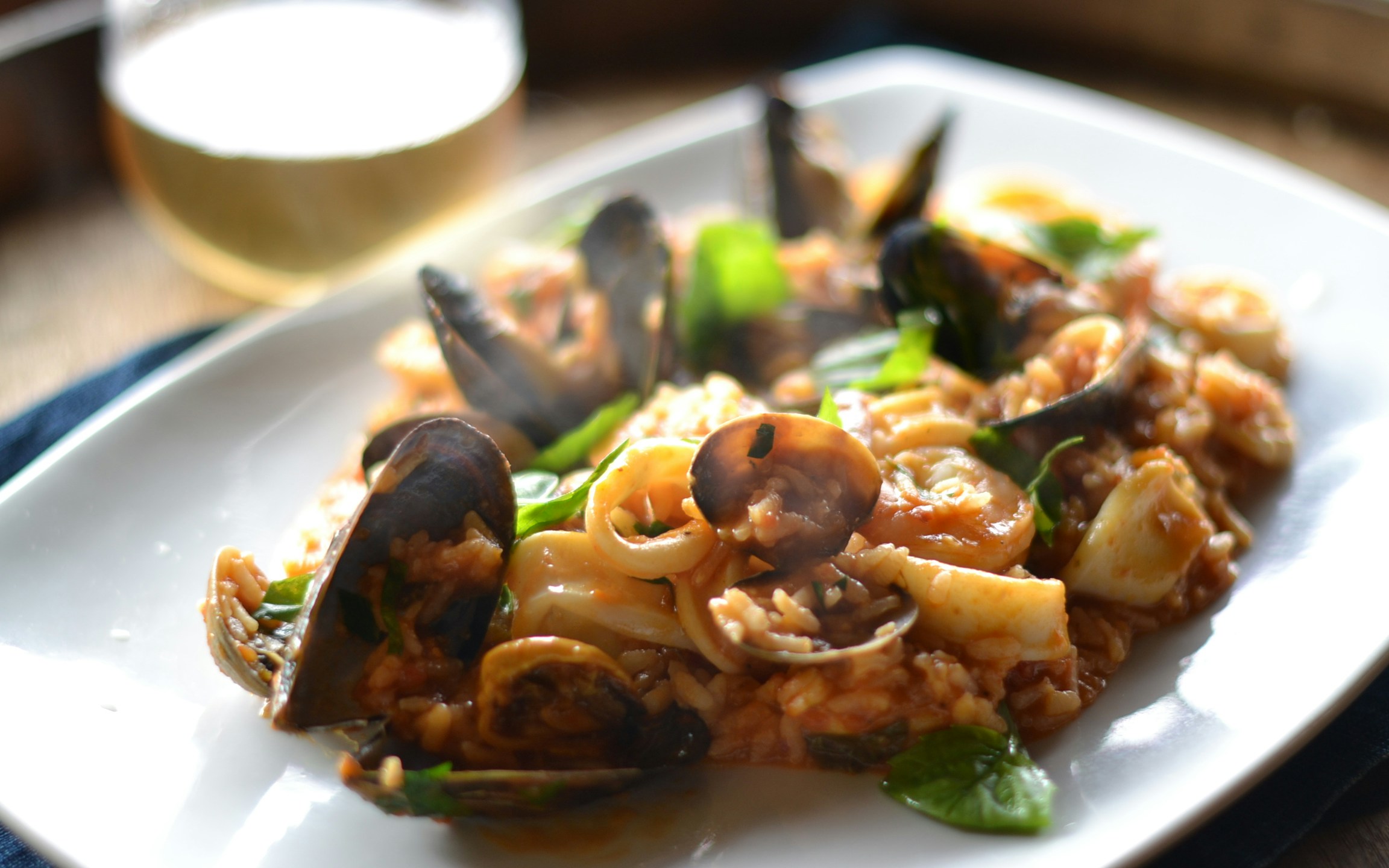 Seafood paella with mussels and squid on a white plate, part of Dine With a Local experience.