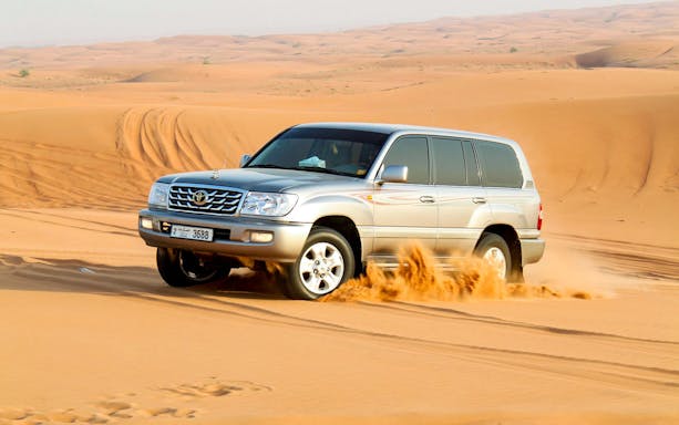 SUV driving through desert dunes during a safari tour.