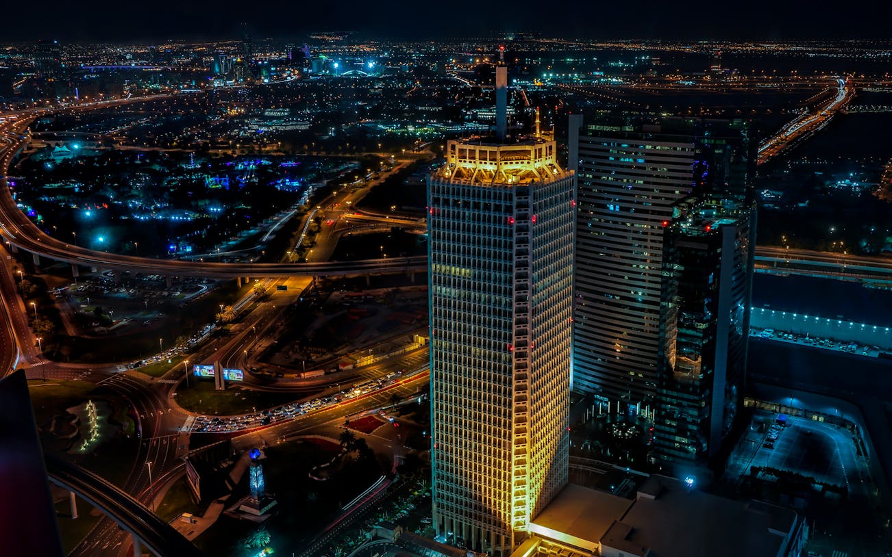 Dubai cityscape at night with illuminated skyscrapers and highways.