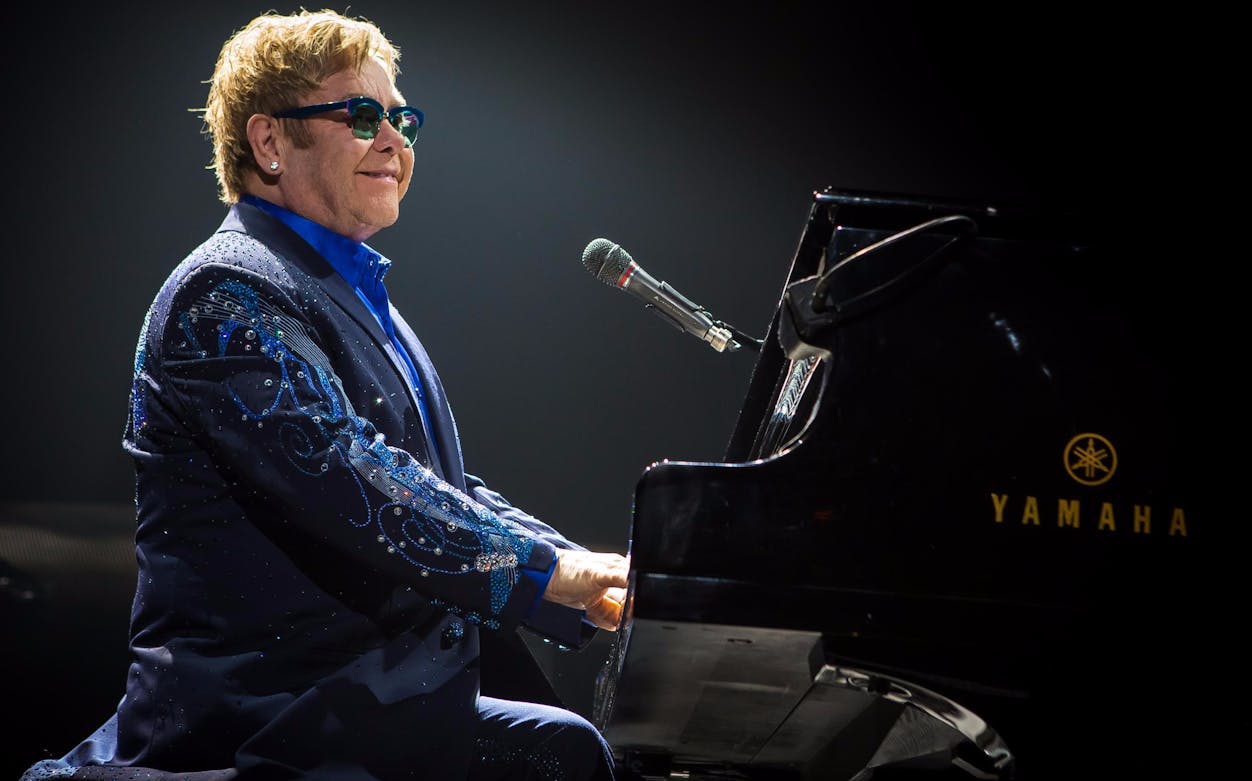 Musician playing piano on stage during a live performance.