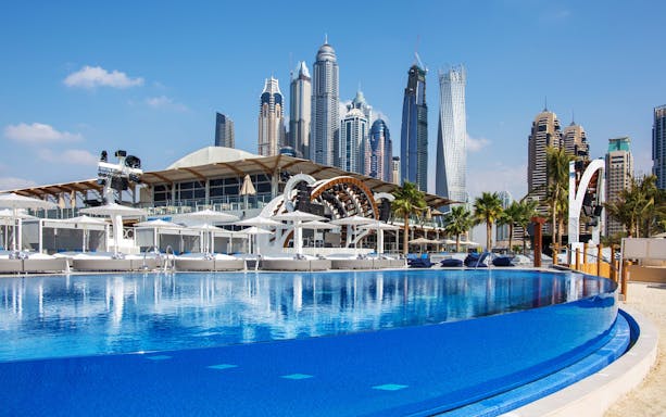 Dubai Marina skyline with luxury beach club and pool.