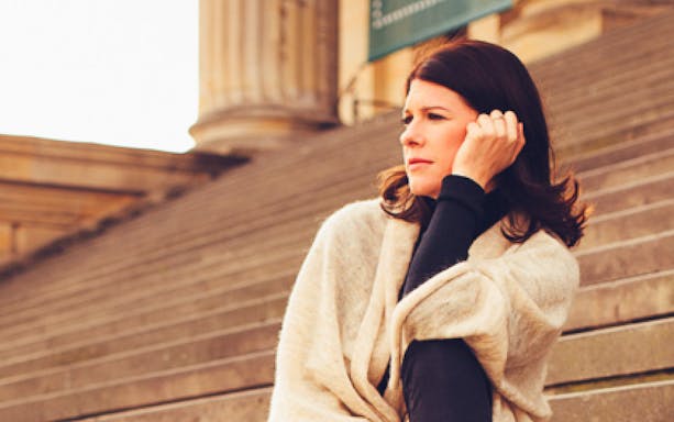 Person sitting on steps outside a concert hall, related to Christmas Gala Concert.