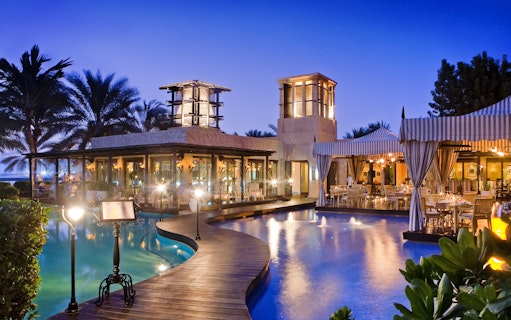 Outdoor dining area by a pool at sunset, set for a Christmas Gala Concert.