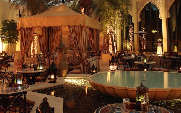 Elegant outdoor seating with lanterns and a fountain at a Christmas Gala Concert venue.