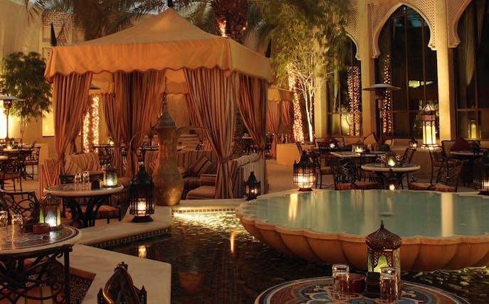 Elegant outdoor seating with lanterns and a fountain at a Christmas Gala Concert venue.