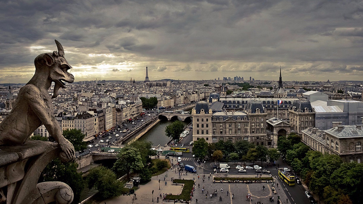 Gargoyle overlooking Paris skyline from Notre Dame Cathedral with Eiffel Tower in view.