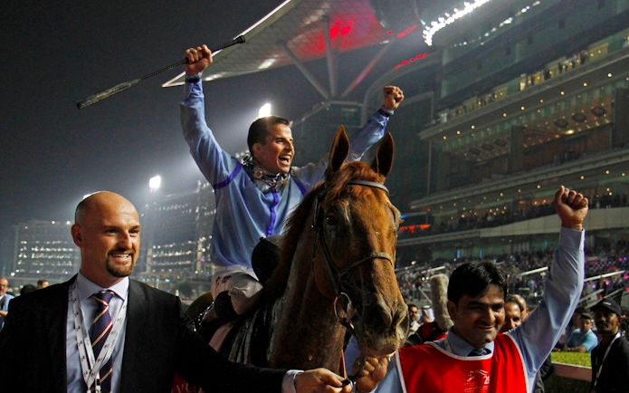 Jockey celebrating victory at Meydan Racecourse in Dubai.