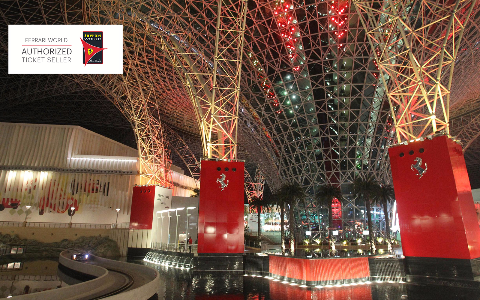 Ferrari World Abu Dhabi interior with red and steel architecture, featuring palm trees and water features.