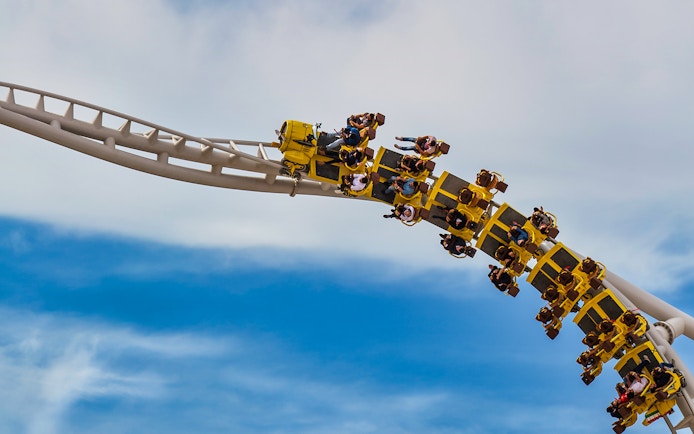 Roller coaster at Ferrari World Abu Dhabi with riders on a loop against blue sky.