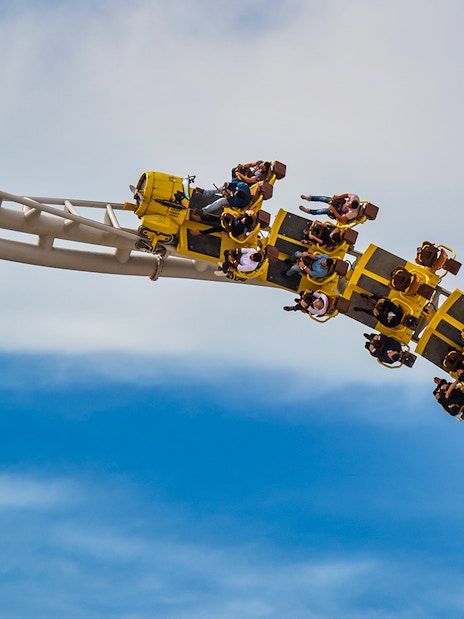 Roller coaster at Ferrari World Abu Dhabi with riders on a loop against blue sky.