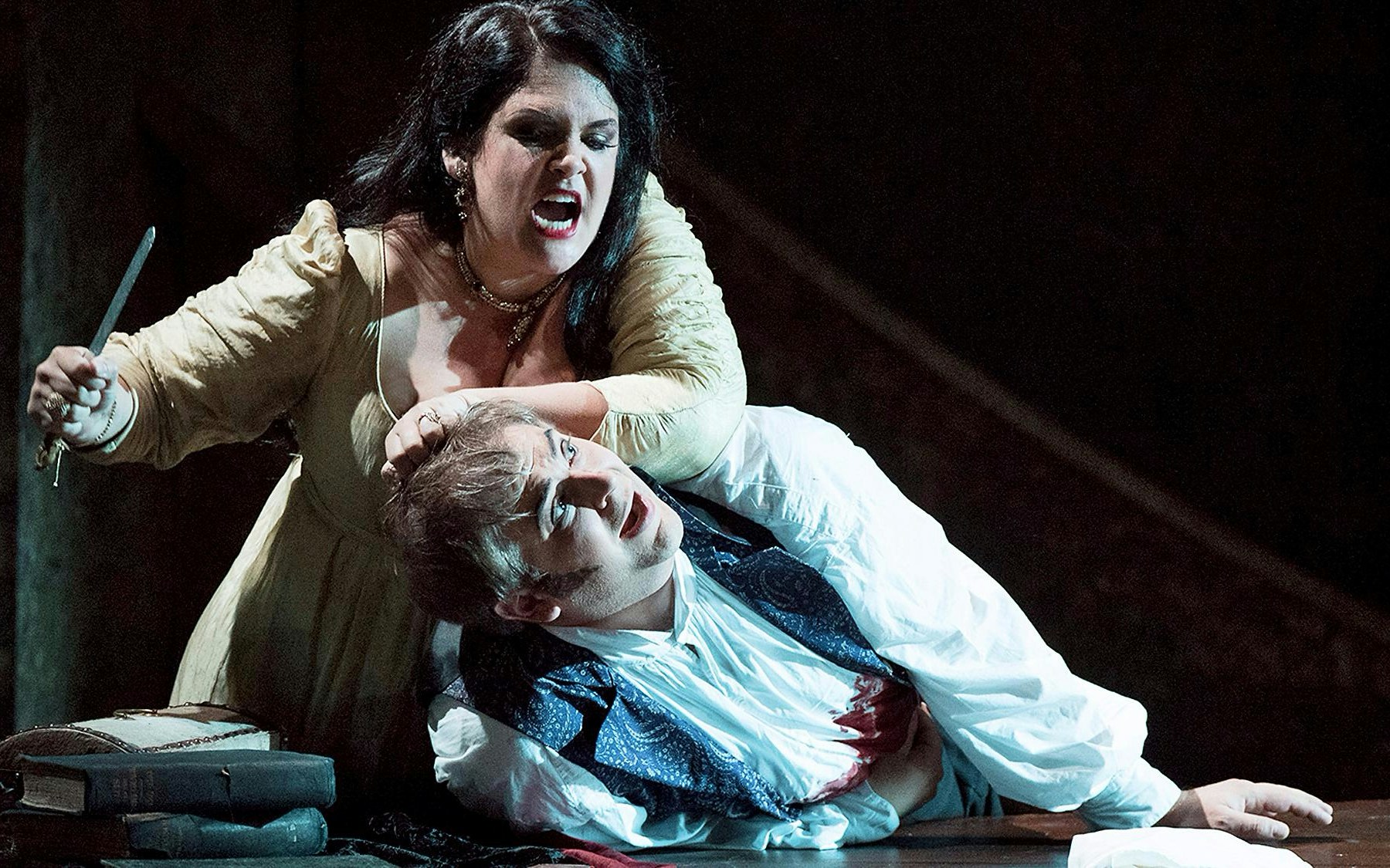 Performers on stage during a Tosca opera in London, showcasing dramatic lighting and elaborate costumes