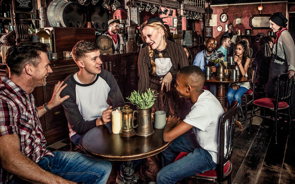 Visitors enjoying drinks with performers at London Dungeon tavern.