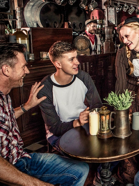 Visitors enjoying drinks with performers at London Dungeon tavern.