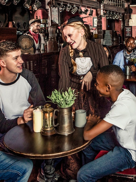 Visitors enjoying drinks with performers at London Dungeon tavern.