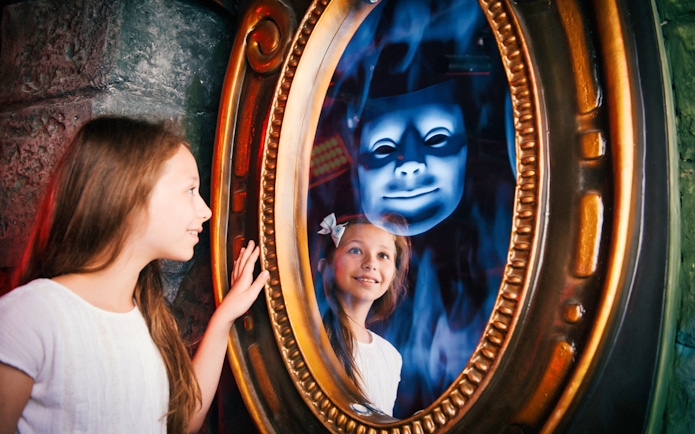 Child interacting with magic mirror at Shrek's Adventure London.