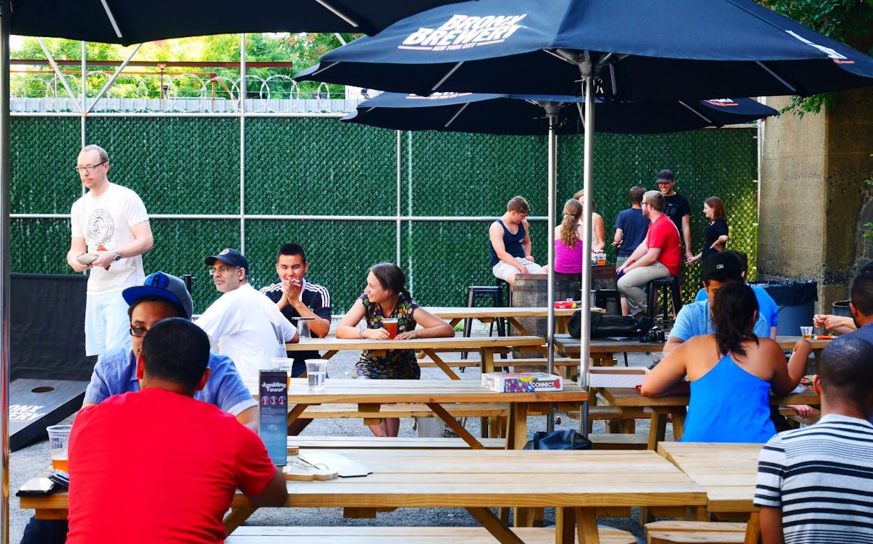 Outdoor seating area at a New York brewery with people enjoying drinks.
