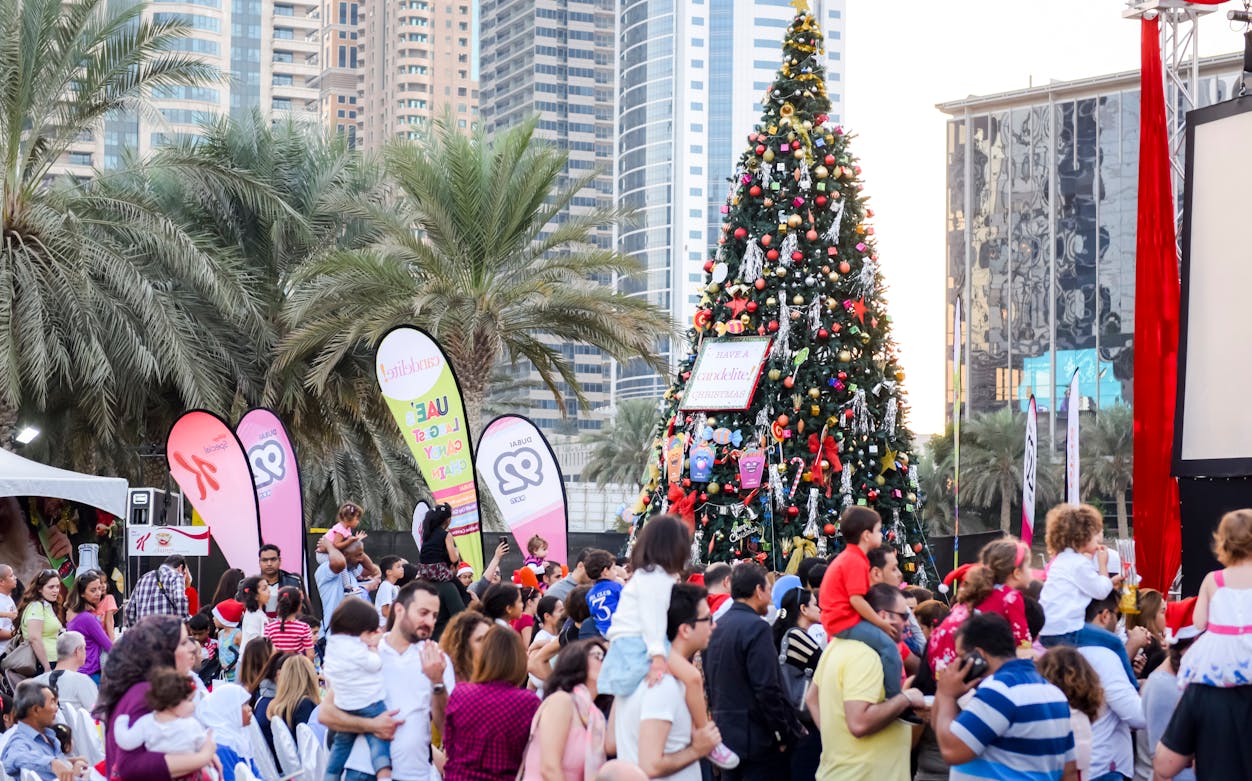 Crowd enjoying Dubai Winter Festival 2016 with decorated Christmas tree and city skyline.