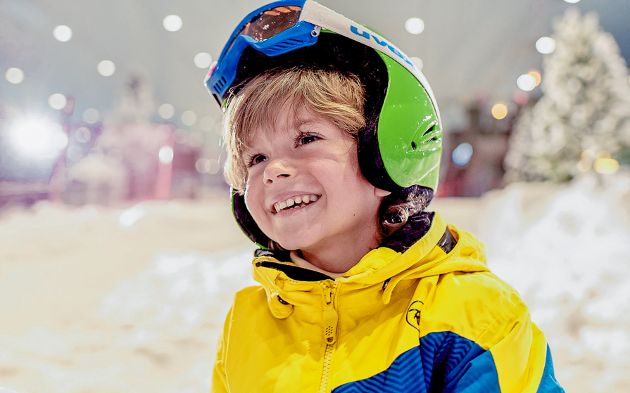 Child smiling in ski gear at Ski Dubai indoor snow park.