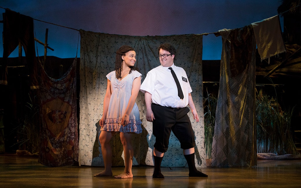 Actors performing a scene from "The Book of Mormon" musical on stage.