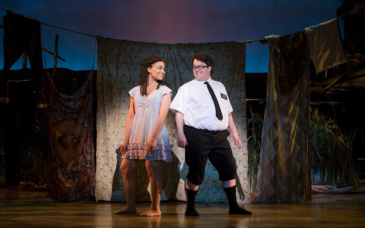 Actors performing a scene from "The Book of Mormon" musical on stage.